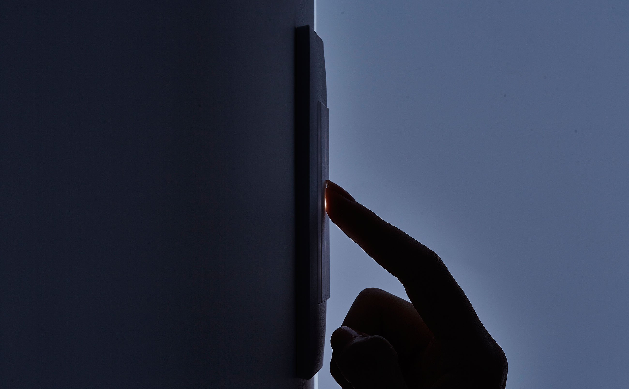 暗闇の中壁面のスイッチをタッチしている人差し指