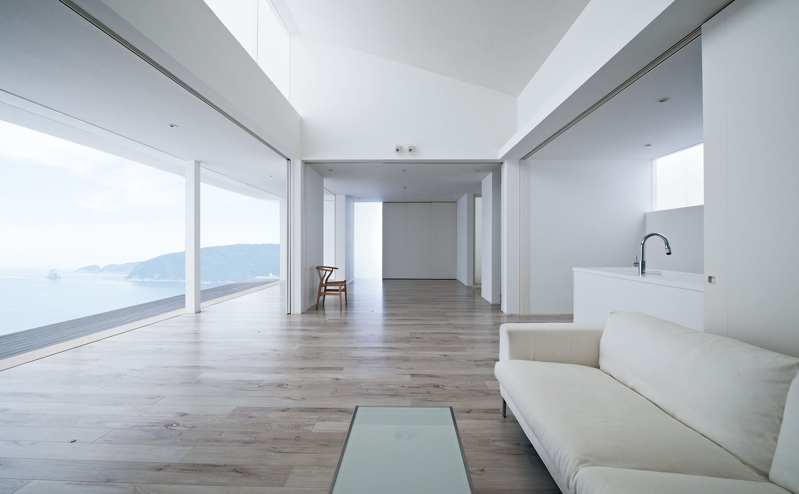 右手に白いソファとキッチンが見えている海に面した建物の室内