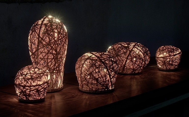 木製のテーブル上に配置された編み込みの照明器具と白熱灯、暗い背景  