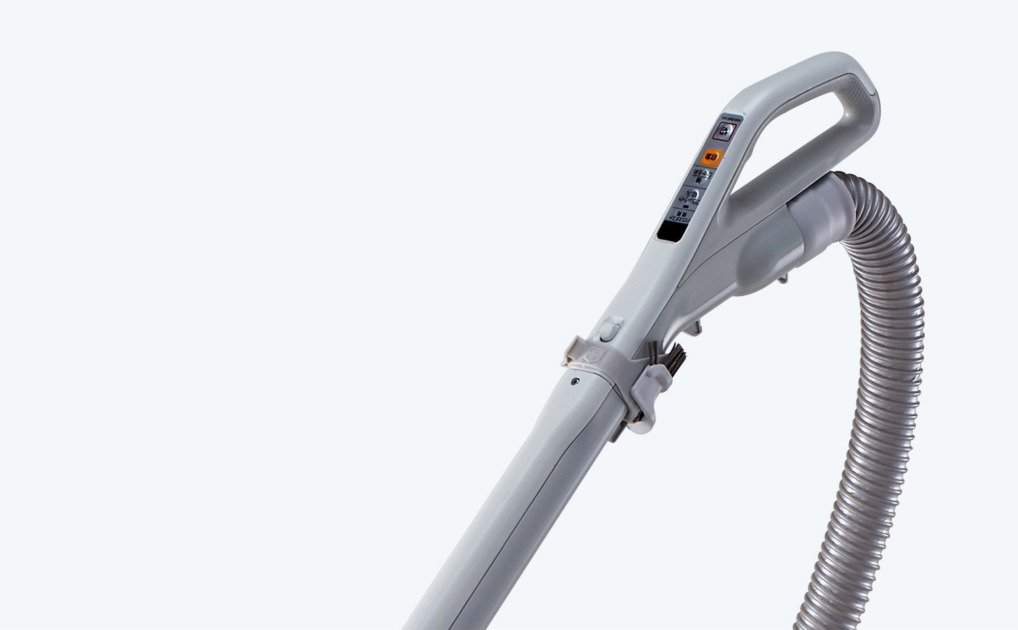 グレーのプラスチック製ハンドルと曲がり伸縮可能な蛇腹状ホースを持つ掃除機の吸引口付近部分