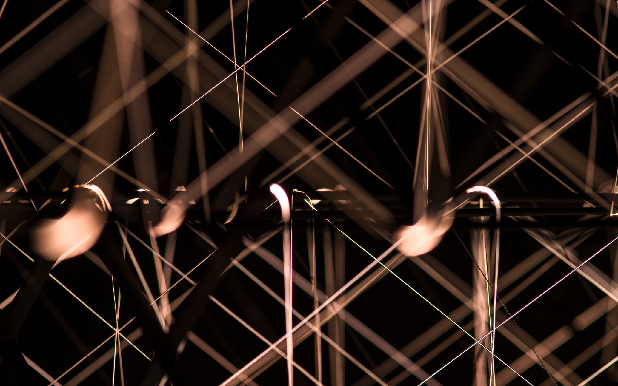 黒背景に交差する金属製の棒と光の線、立体的な構造のアップ