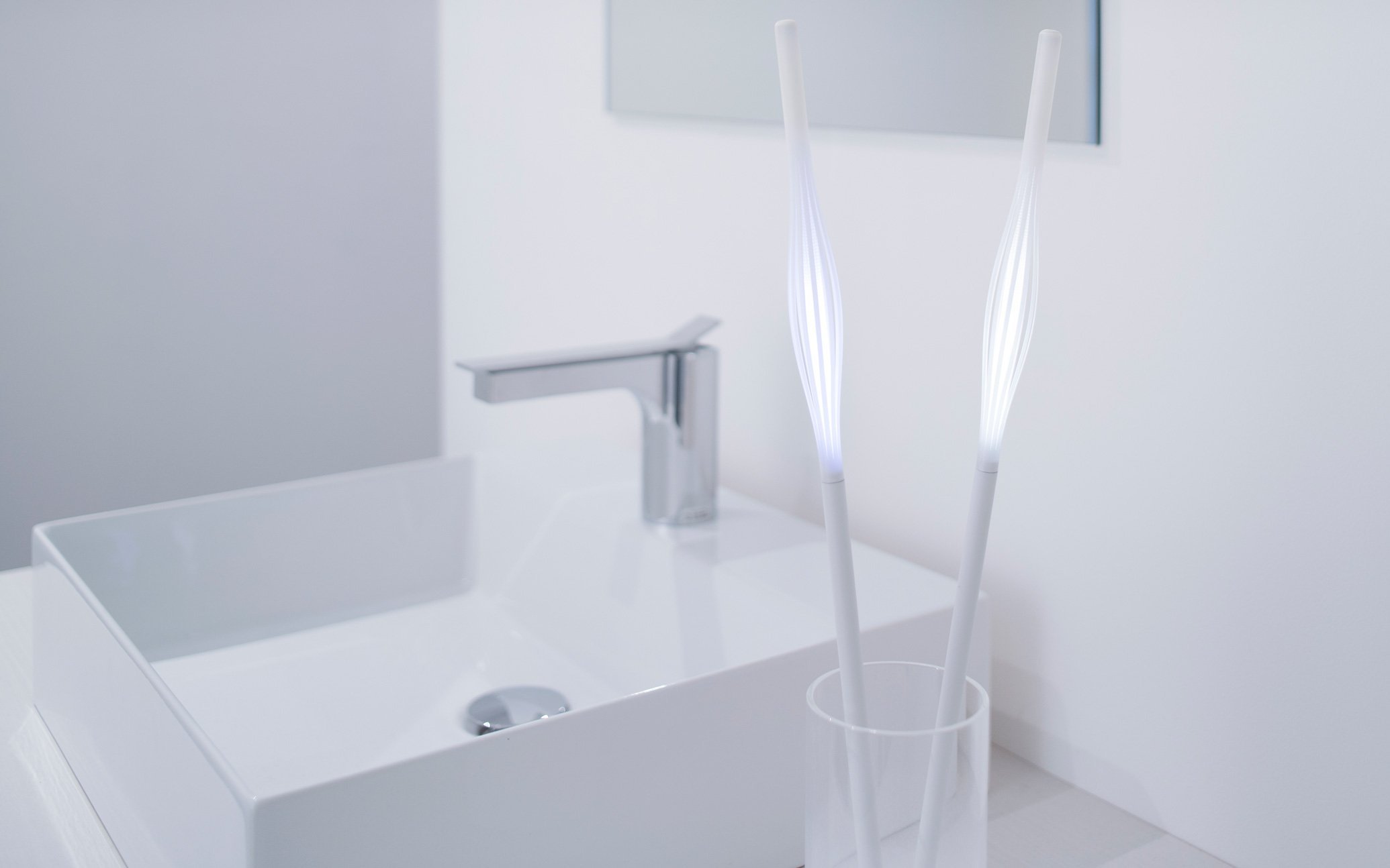白い洗面台と蛇口の横に立つ二本の照明器具のアップ