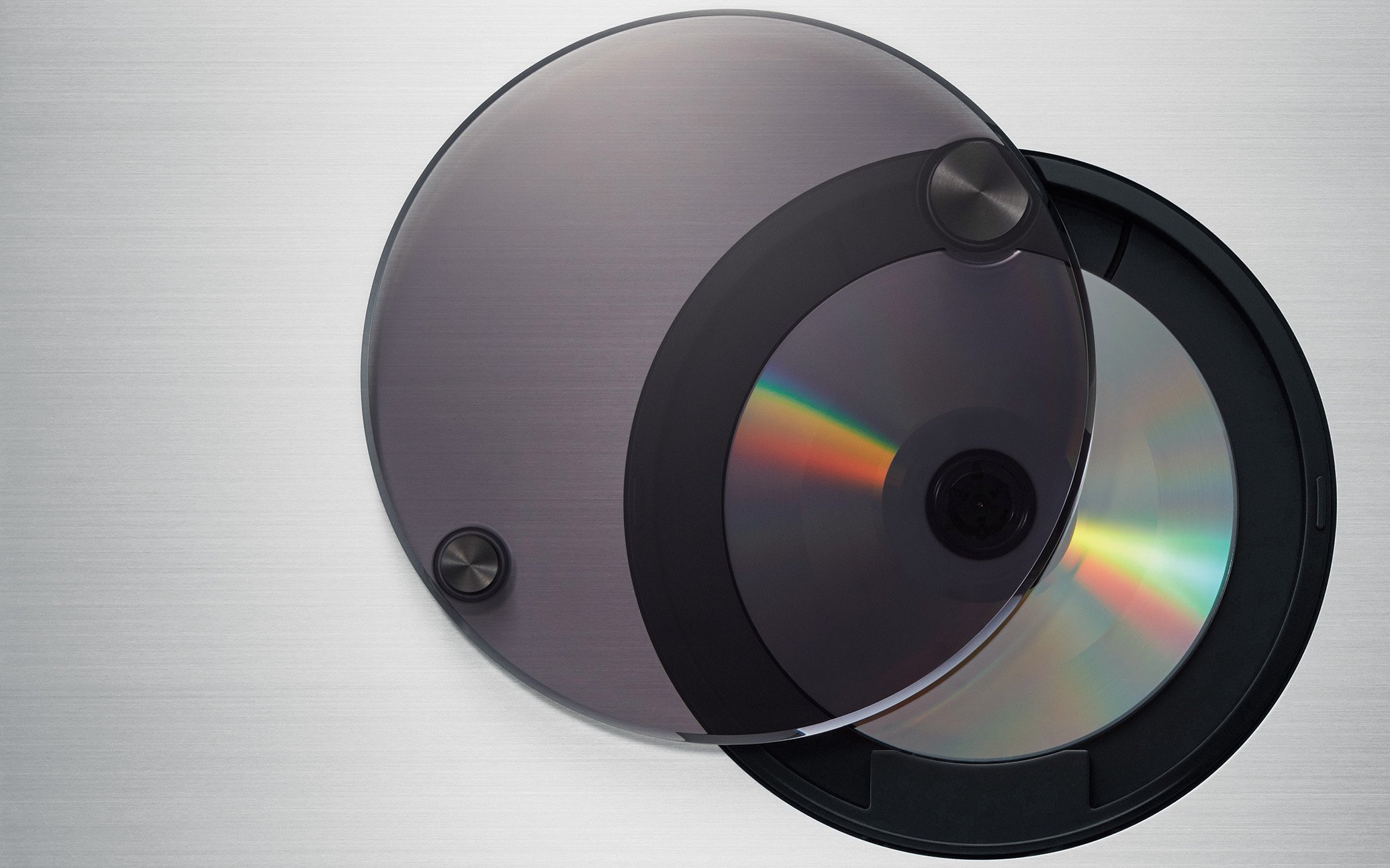 グレーの円形のディスクに透明なカバーをかぶせたCDプレーヤーの上面とディスクのアップ