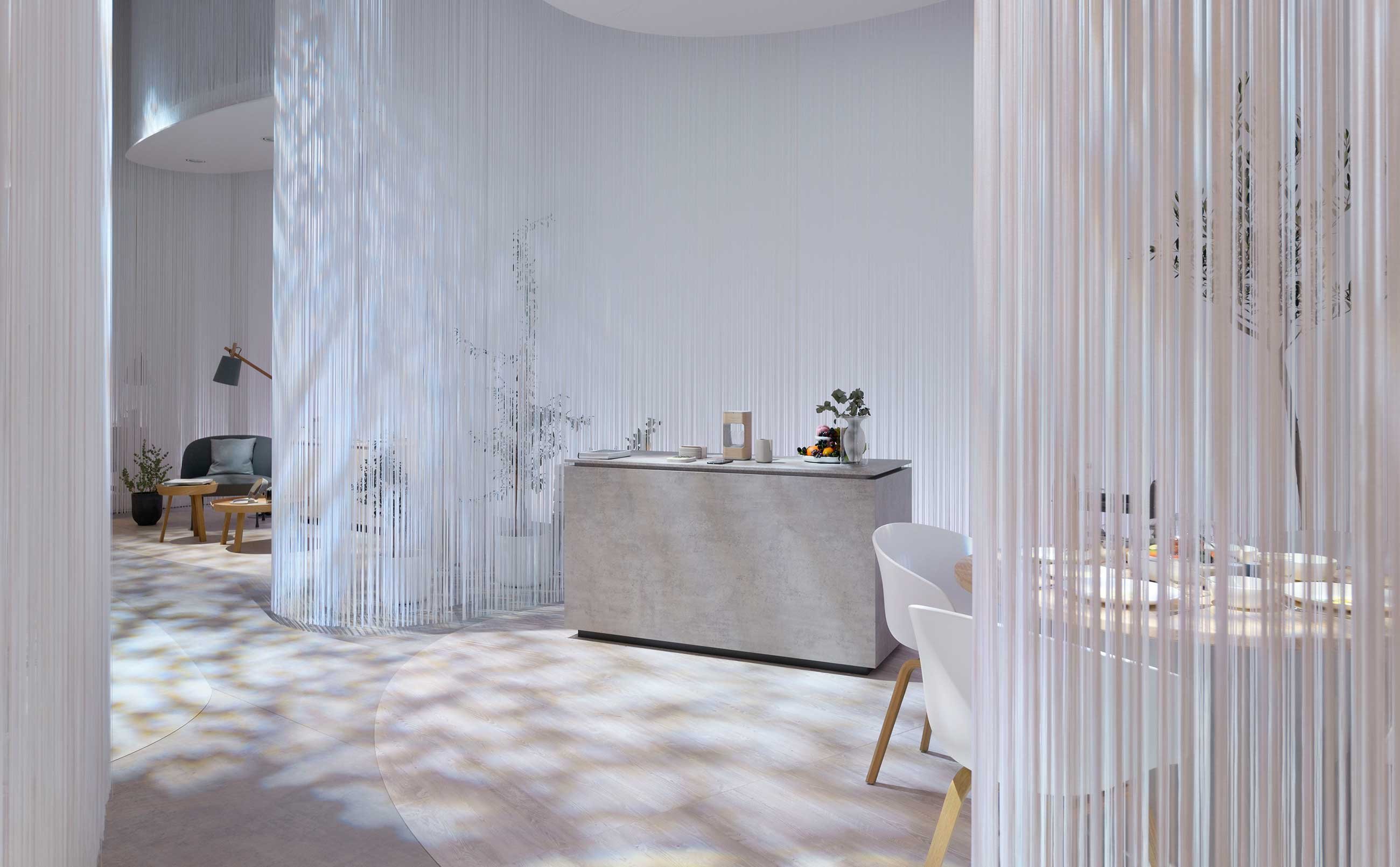 白いすだれ状のカーテンに囲まれてキッチンカウンターとダイニングテーブルがある