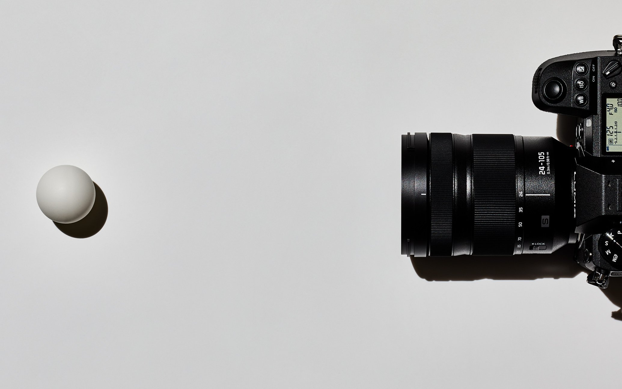 カメラと白い球体のオブジェクトが並ぶシンプルな構図