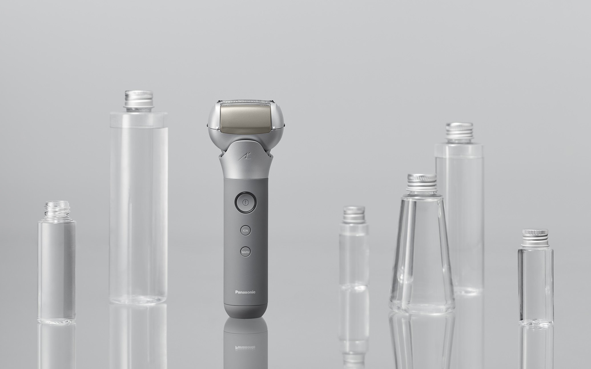 グレーの電気シェーバーと透明な容器が並ぶシンプルな正面画像