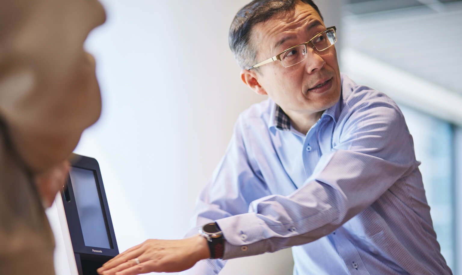 男性がカードリーダー端末を操作しながら会議で説明している様子