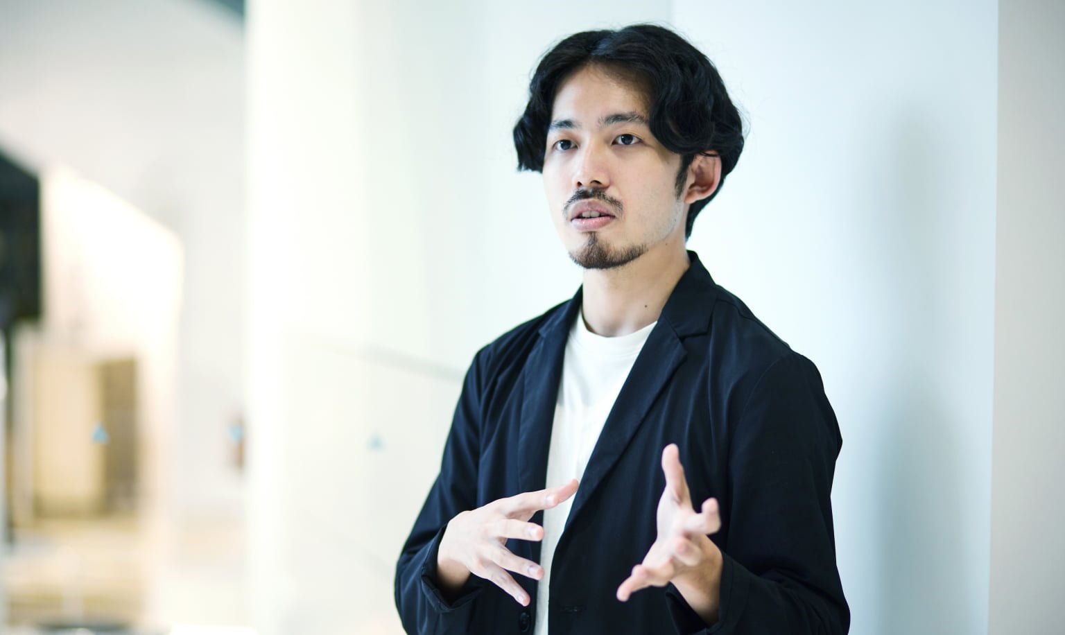 ネイビーのジャケットを着た男性（安久）が手振りを交えて話をしている