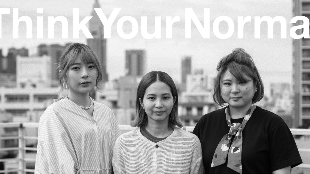 3名の女性が都会のビルの屋上で並んでいるモノクロ画像