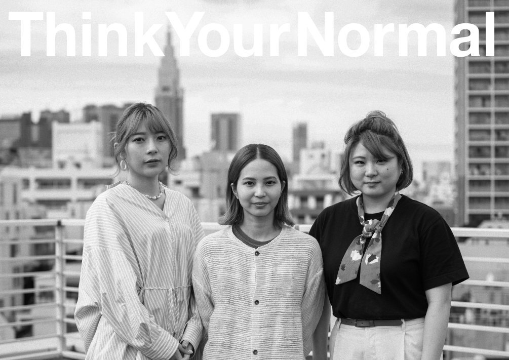 都市の屋上で並ぶ三人の女性と「Think Your Normal」のメッセージビジュアル