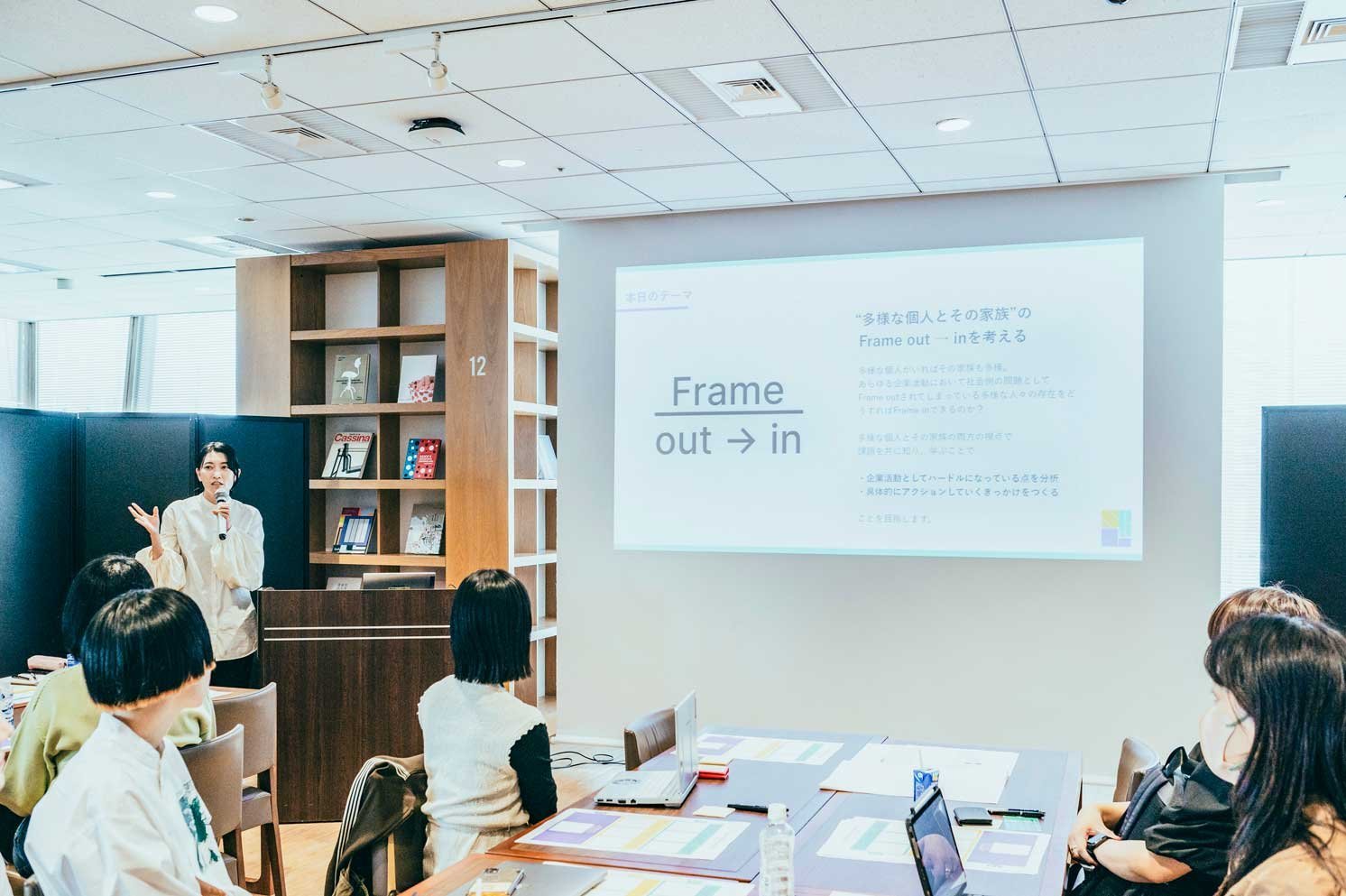 スクリーンに「Frame out → in」と表示されたスライドと登壇者