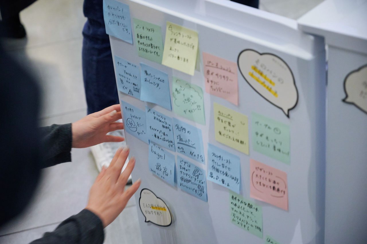 白い冷凍庫の扉に、手書きでメッセージが書かれたカラフルな付箋と吹き出しスタイルのメモが貼られている。