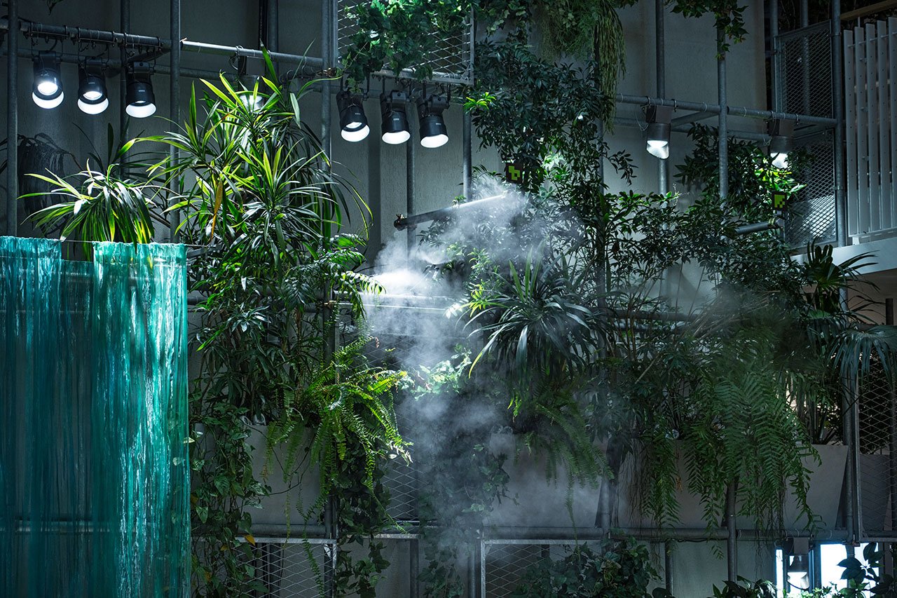 壁面の植栽にミストで水やりしている様子　スポットライトの照明が植栽を照らしている