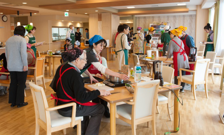 写真：サービス付き高齢者住宅で家電を使った料理教室で老人とふれあう中尾洋子