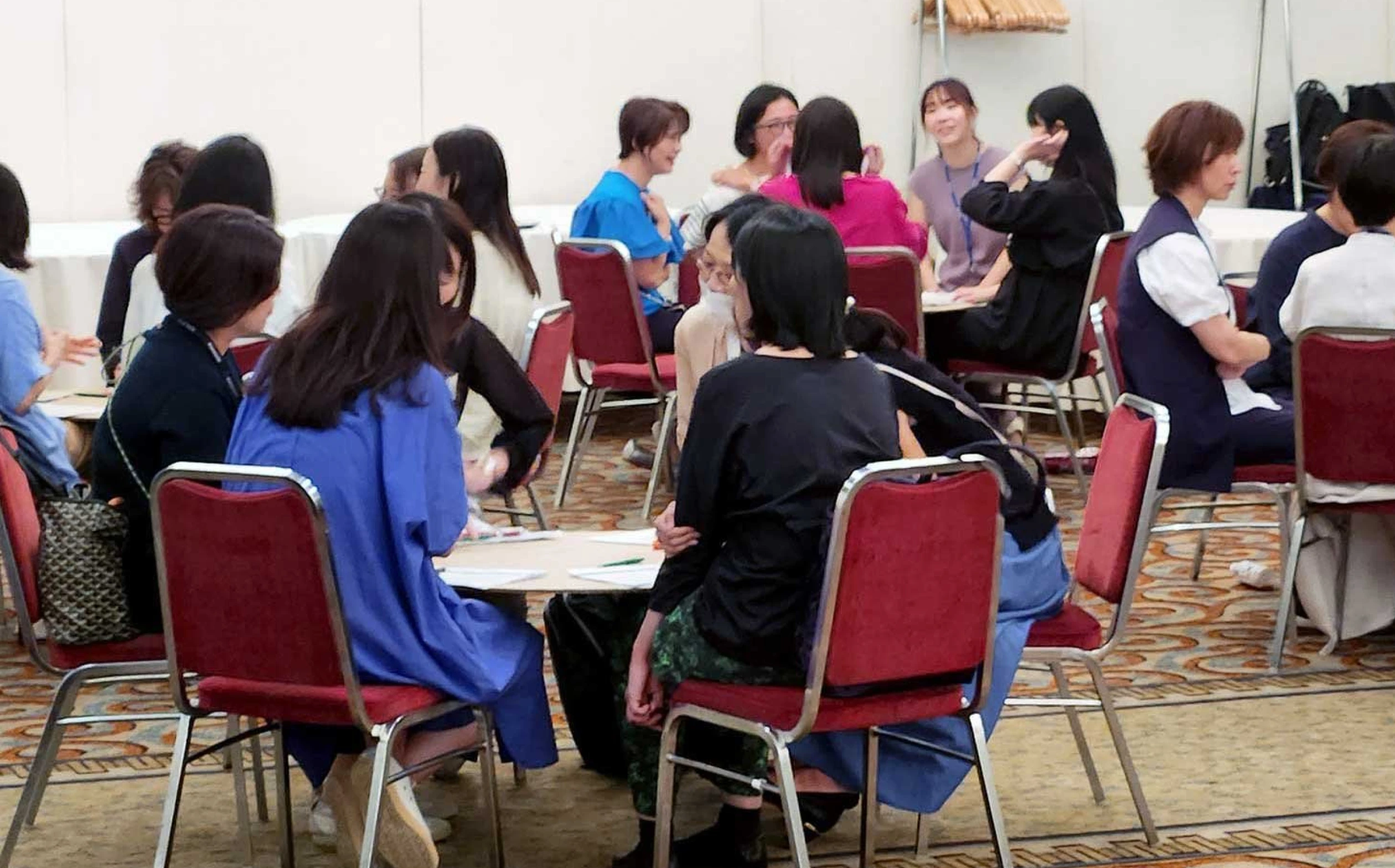 写真：大勢の女性達が集まって6人程度のグループに分かれ話し合っている様子