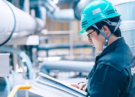 パナソニック環境エンジニアリング株式会社 プラント施設内で書類に目を通すエンジニア