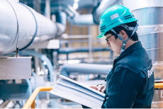 プラント施設内で書類に目を通すエンジニア