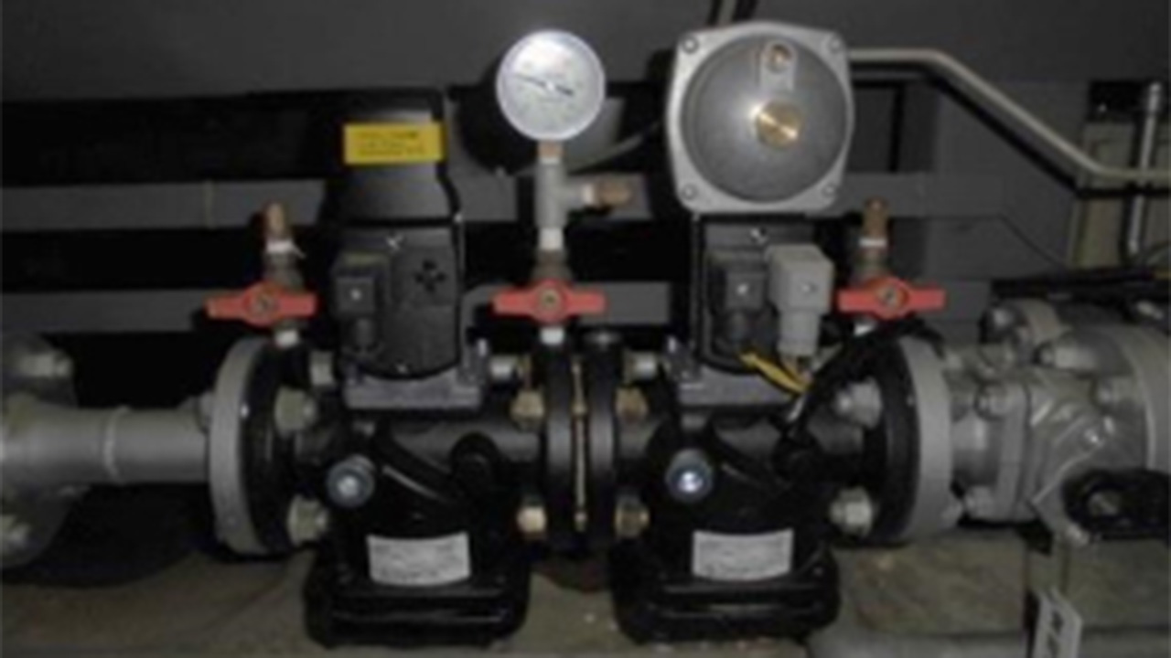 ガス焚燃焼安全部品の一つであるメイン遮断弁の外観。配管に組み込まれた黒いバルブ本体と、その上部に設置された制御ユニットや圧力計の様子。