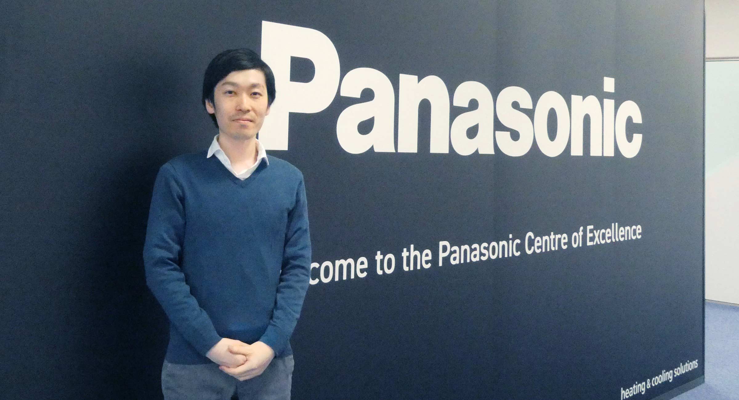 Panasonicの会社ロゴの前に立つ小林の画像