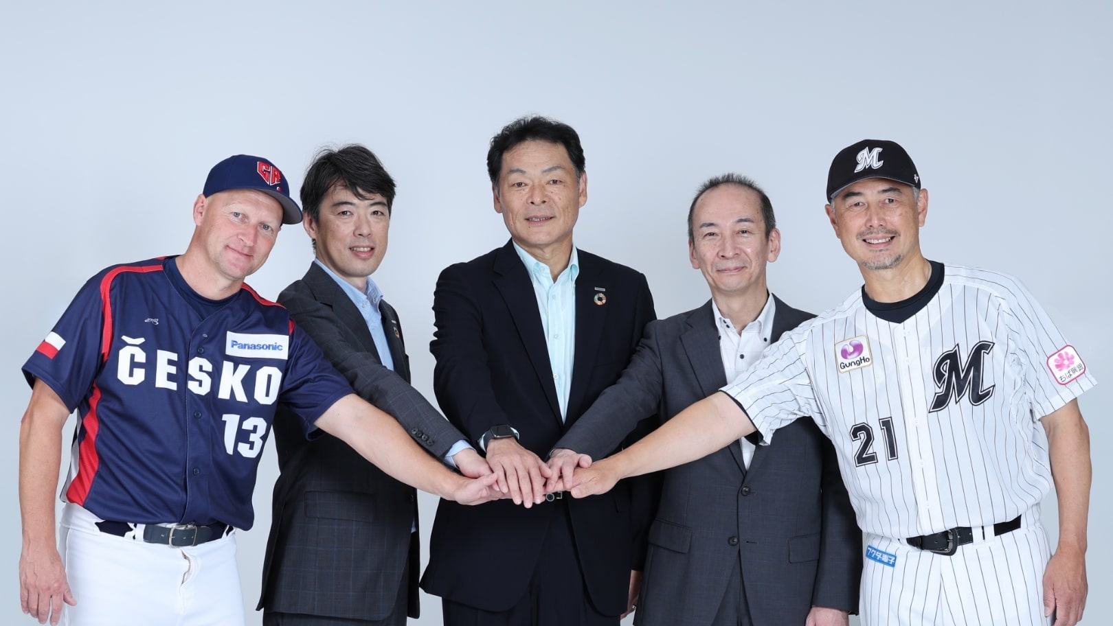 空質空調社の道浦社長と役員2名、マリーンズ監督、WBCチェコ監督が手を取り合い「マリーンズ-チェコ ベースボールブリッジプログラム」に協賛する画像