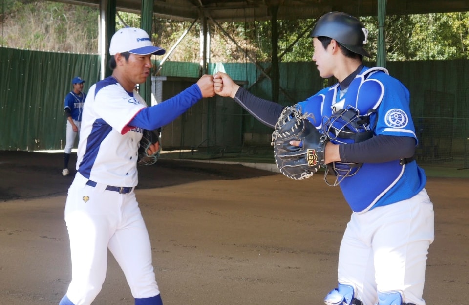 投球練習後に延世大学の捕手とグータッチを交わす與座健人投手（右写真の左）