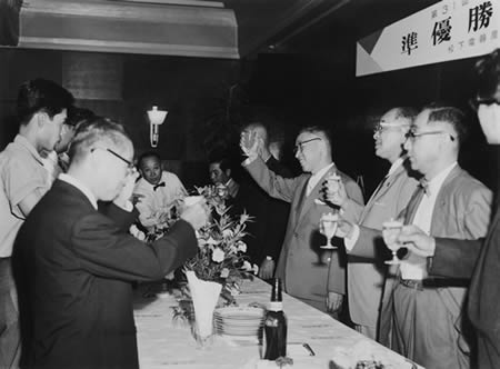 Celebratory gathering to praise the team's efforts in taking second place. Konosuke Matsushita making a toast along with executives and team members. August 10, 1960.