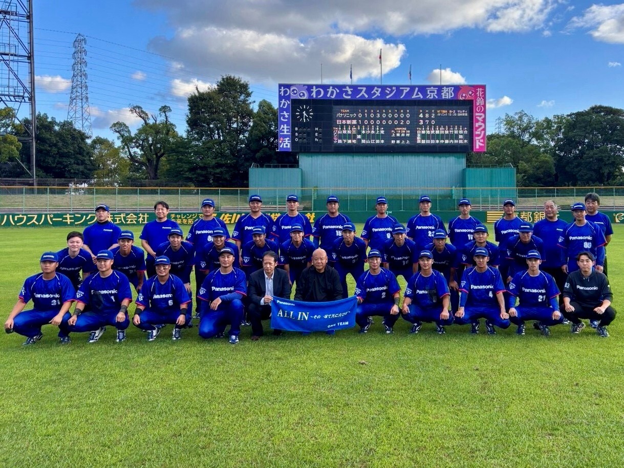 写真：わかさスタジアム京都のスコアボードの前で、「ALL IN」の横断幕を持って並ぶパナソニック野球部の選手・スタッフ