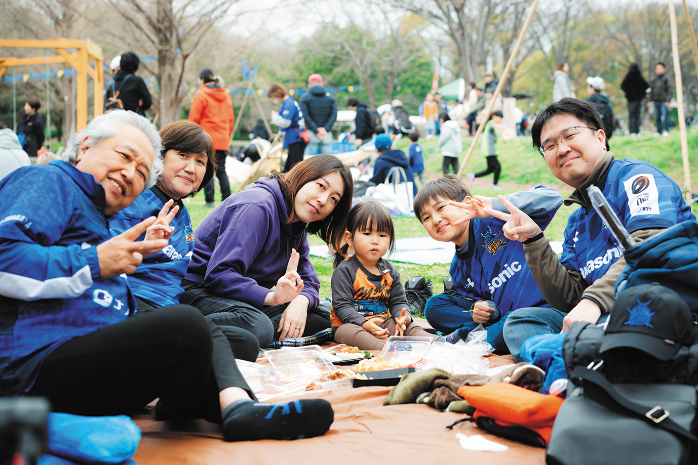 ピースサインをしているピクニック中のサポーターファミリー