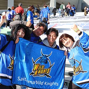 ユニフォームを着て応援旗を持つ楽しそうな男女４人