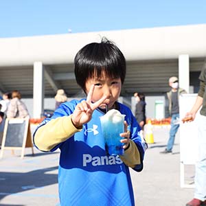 青いクリームソーダを持ってピースしているユニフォームを着た少年